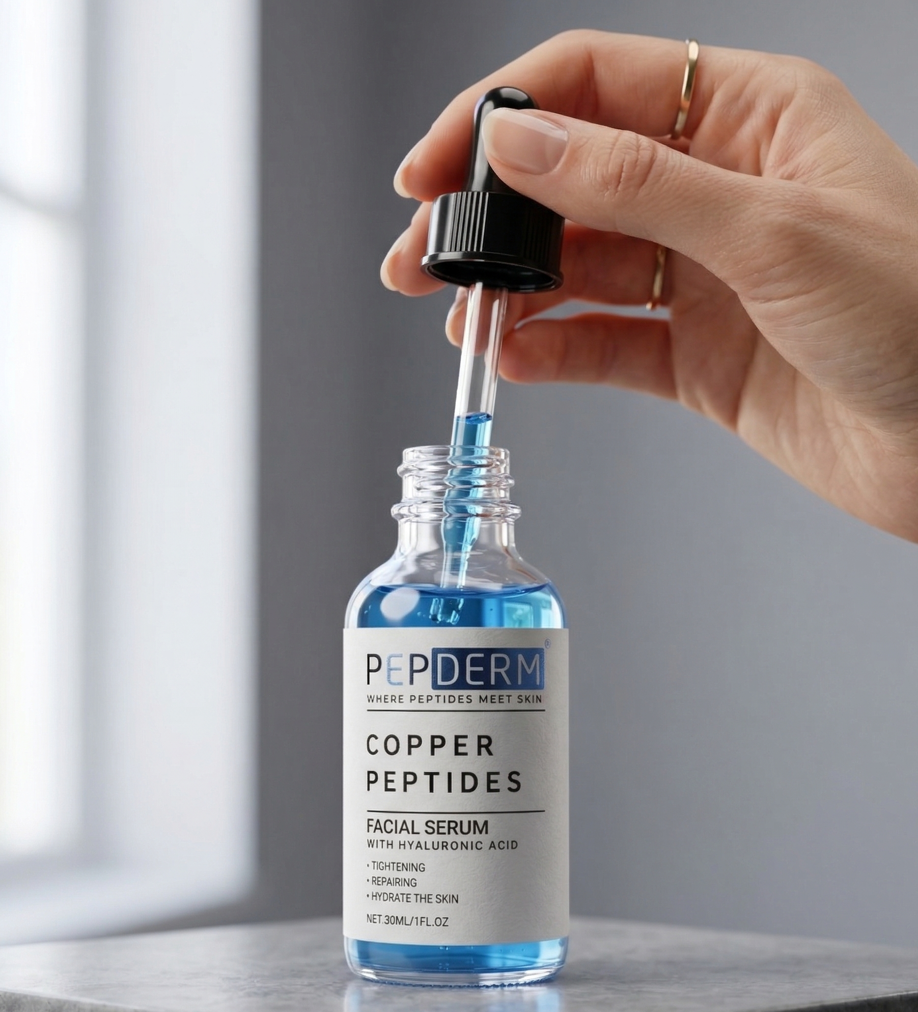 Hand holding a dropper over a bottle of Peiderm Copper Peptides Facial Serum on a neutral background
